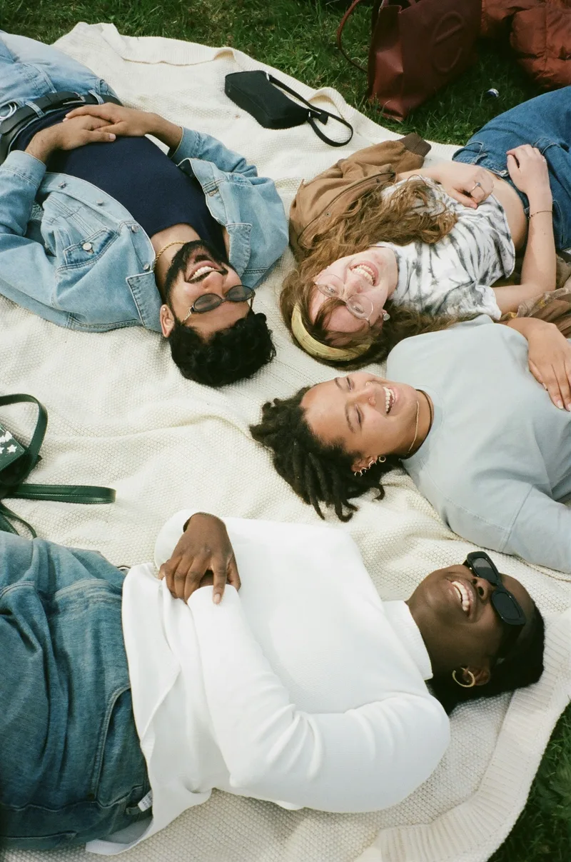 Friends laughing together on a picnic blanket